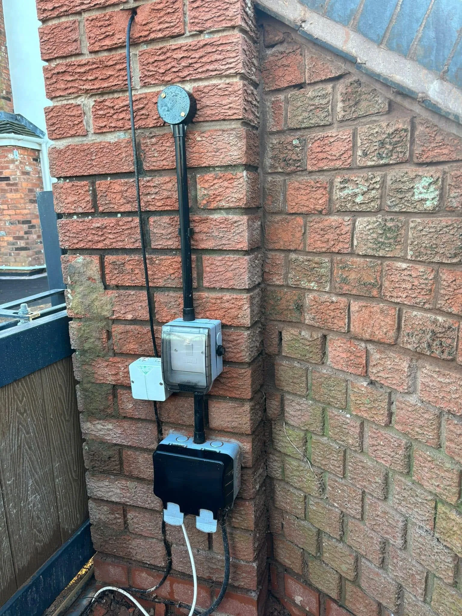 Weatherproof outdoor sockets and an isolator switch mounted on a brick wall