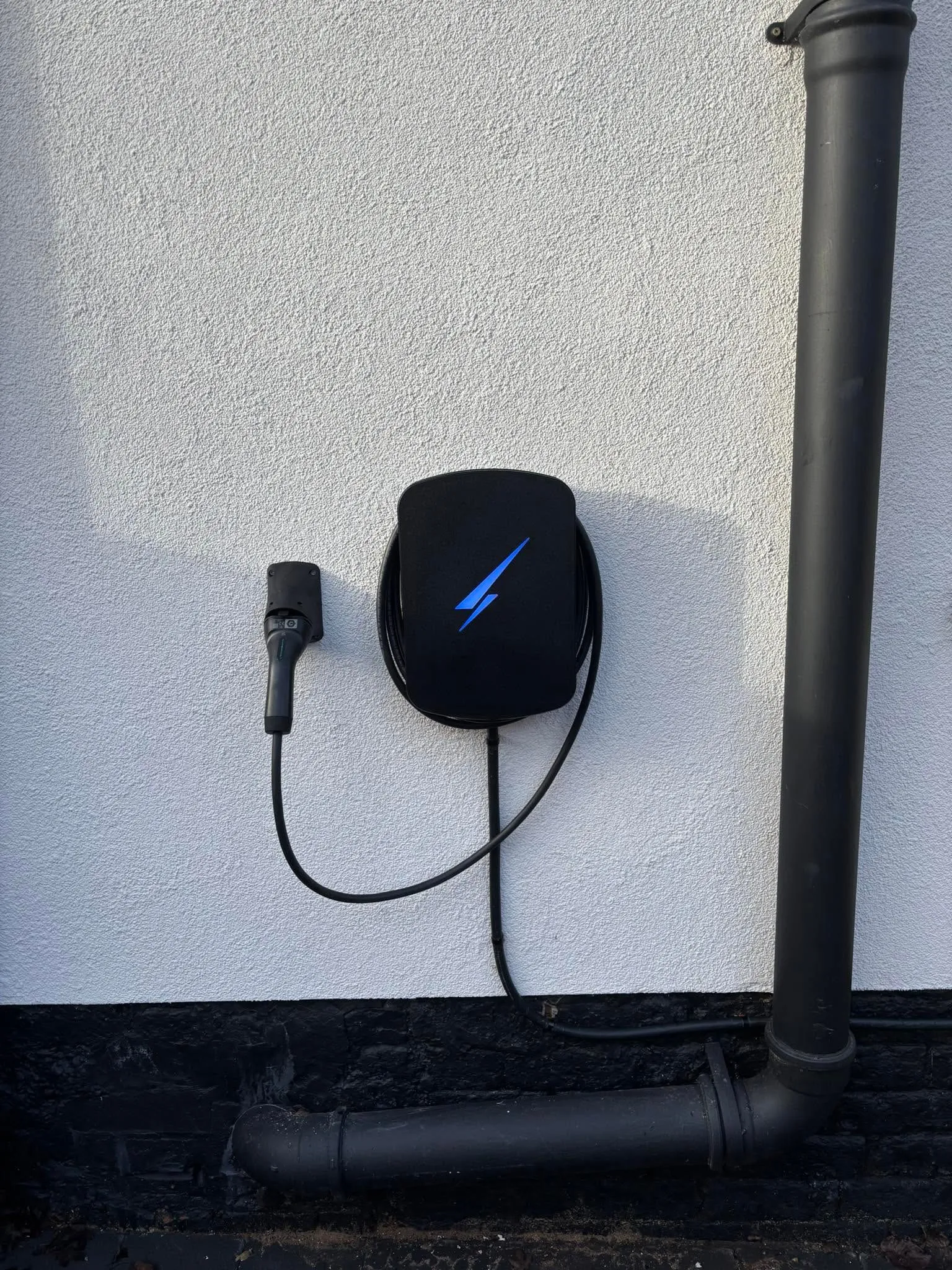 An EV charge point installed on an exterior wall with the cable coiled neatly
